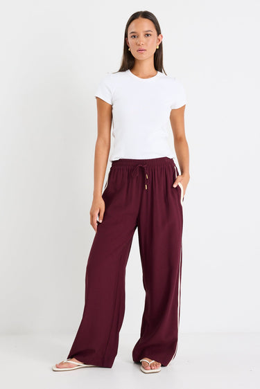 Woman wears a burgundy pant and white top
