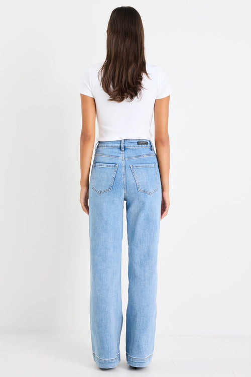 Person wearing light blue jeans and a white shirt on a white background