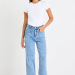 Woman wearing light blue jeans and a white t-shirt on a white background