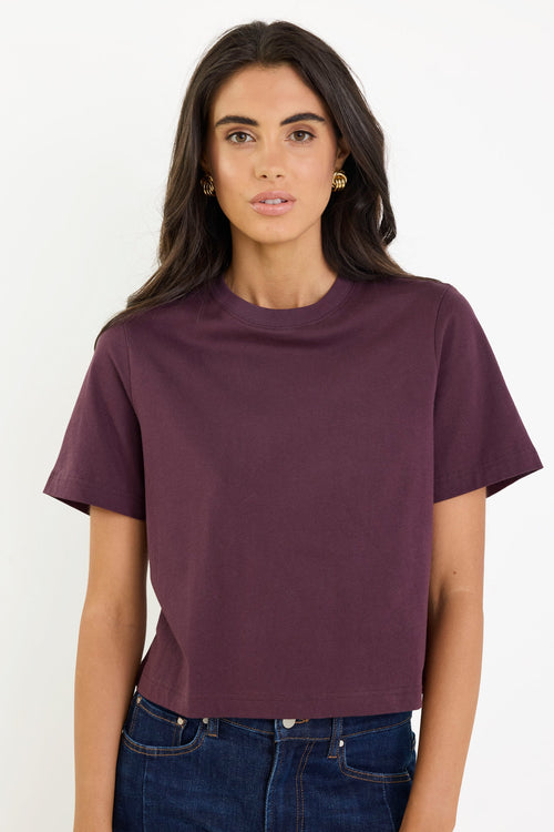 Woman wearing a purple t-shirt and blue jeans on a white background