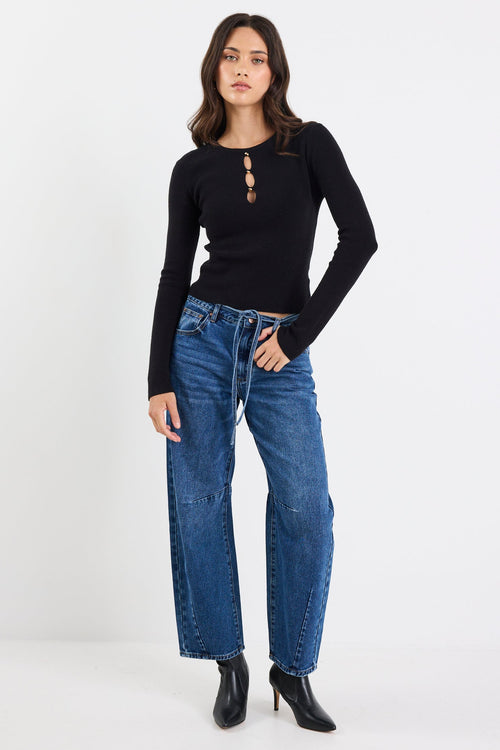Woman wearing a black long-sleeve top and blue jeans on a white background