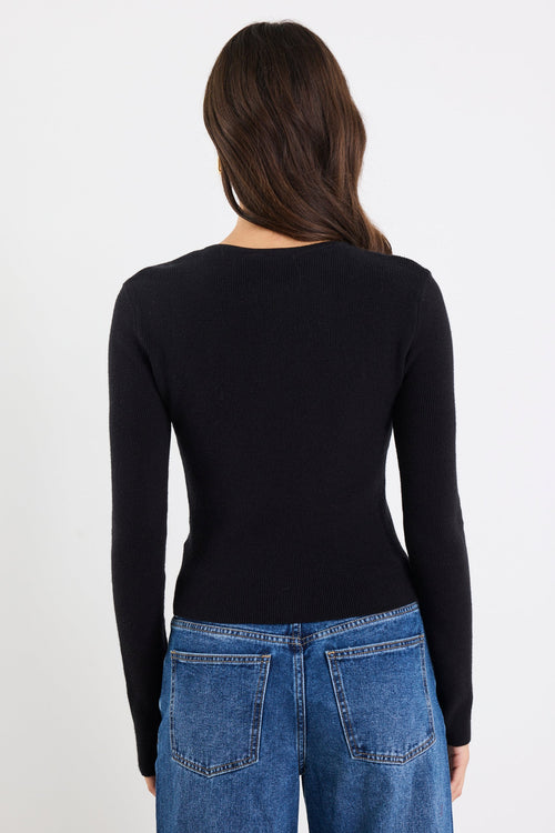 Person wearing a black long-sleeve top and blue jeans on a white background