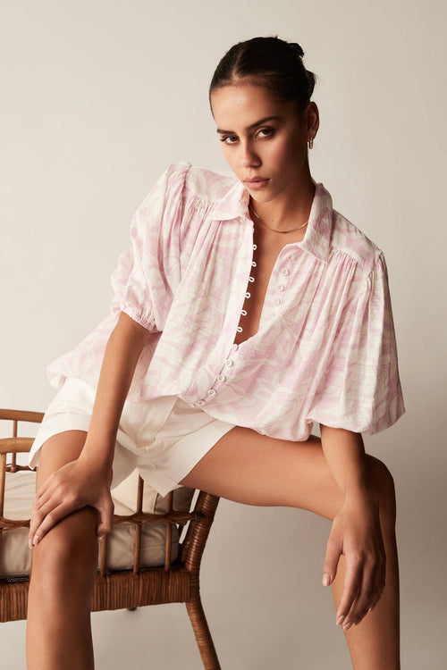 model wears a pink and white blouse