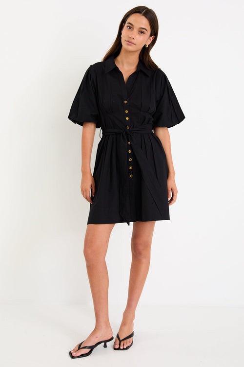 Woman wearing a black dress with buttons on a white background