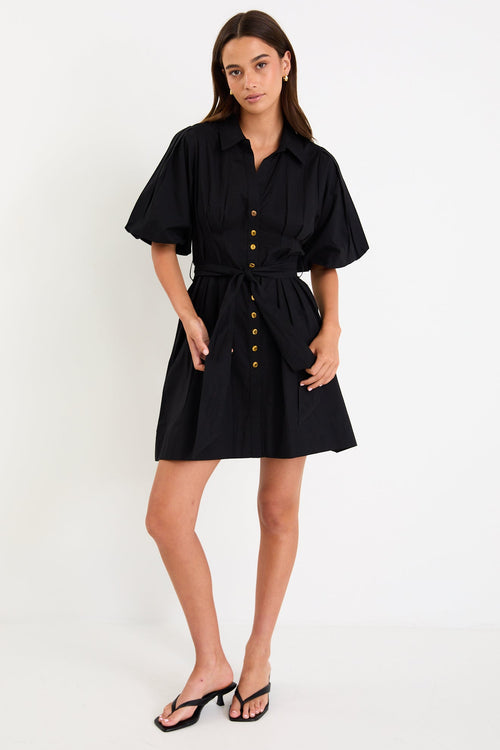 Woman wearing a black dress with buttons on a white background