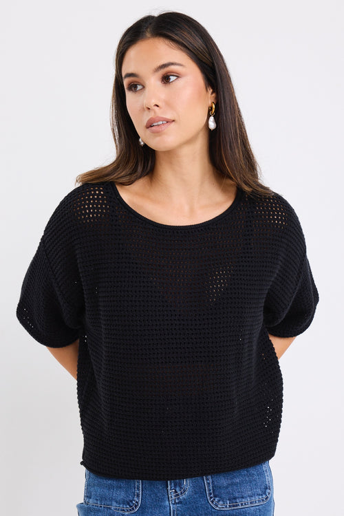 our model wears a black crochet knit top with mid blue jeans
