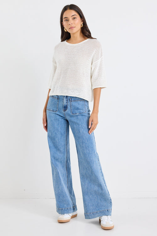 model wears a white knit t-shirt and a light blue jean