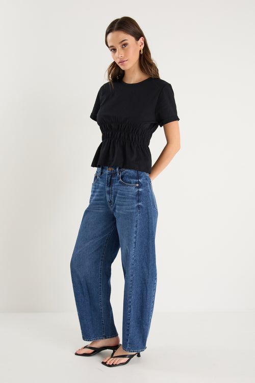 model wearing black shirt and blue jeans