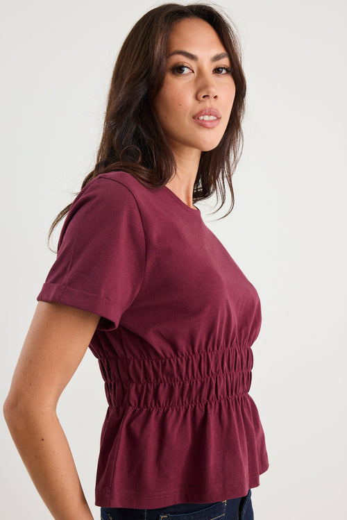 Woman wearing a maroon top against a white background