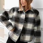 Woman wearing a plaid jacket against a white wall