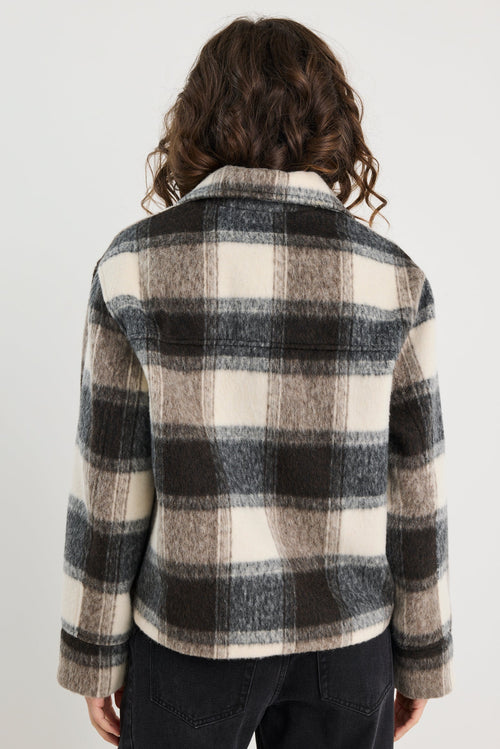 Person wearing a black and white checkered shirt against a plain background