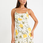 Mini floral bias dress with adjustable straps and a soft, floaty fit, styled with heels and delicate accessories.