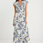 Woman wearing a floral dress with white sneakers on a plain background