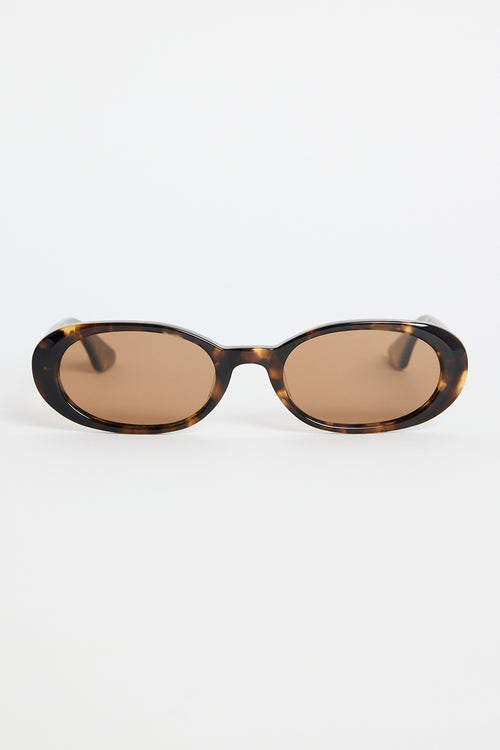 Narrow tortoiseshell oval sunglasses with warm brown tinted lenses, photographed against a white background