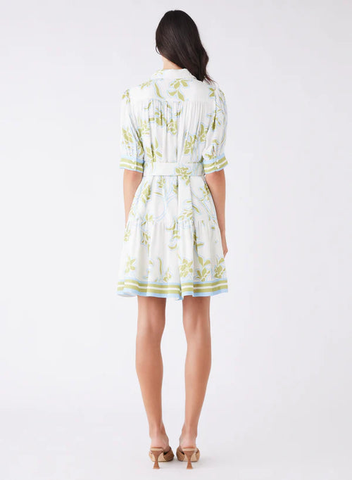 Woman wearing a white dress with green floral pattern on a white background