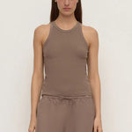 A woman modeling a sleeveless ribbed tank top and matching drawstring pants in a taupe-brown color, set against a plain off-white studio background.