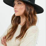 Woman wearing a black hat against a white background