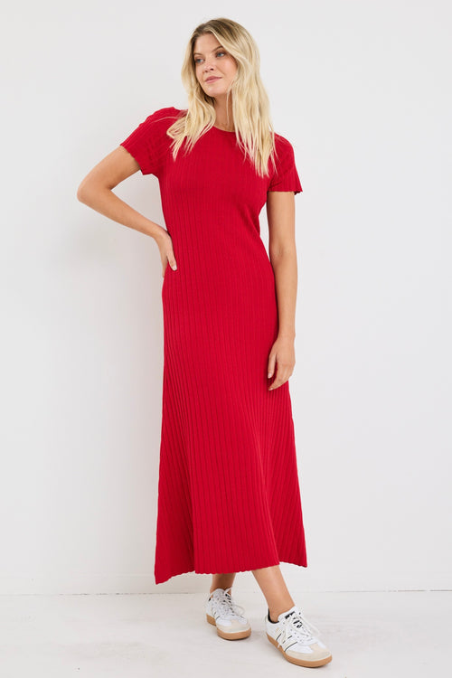 Woman wearing a bright red, ribbed knit dress with short sleeves and crew neckline, styled with white sneakers.
