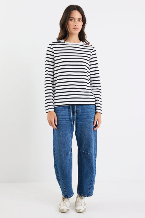 Woman wearing a black and white striped shirt and blue jeans on a white background