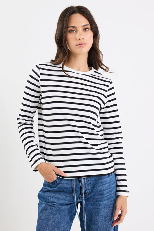 Woman wearing a black and white striped shirt and blue jeans on a white background
