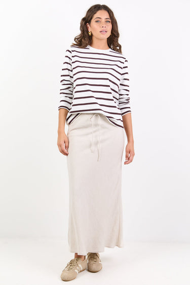 Woman wearing a striped sweater and white pants on a white background