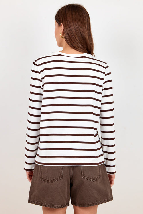 A woman shown from the back wearing a brown and white horizontally striped long-sleeve top and brown shorts against a plain light background.