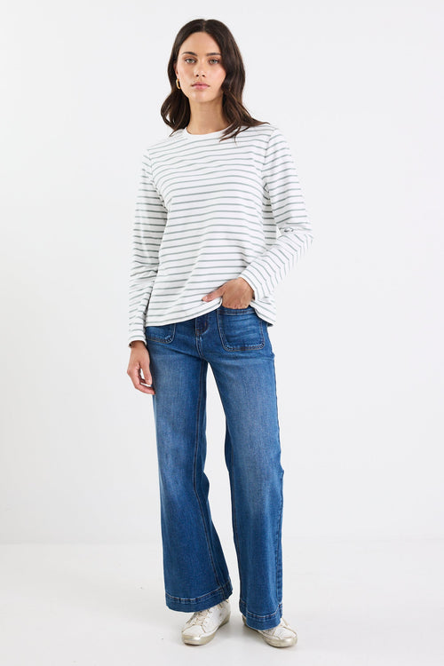 Person wearing a striped sweater and blue jeans on a white background