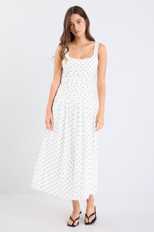 Woman wearing a white dress with black polka dots on a white background