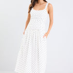 Woman wearing a white dress with black polka dots on a white background