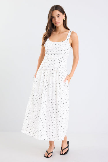Woman wearing a white dress with black polka dots on a white background