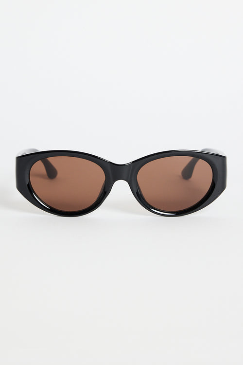 Glossy black cat-eye sunglasses with brown tinted lenses, photographed on a white background