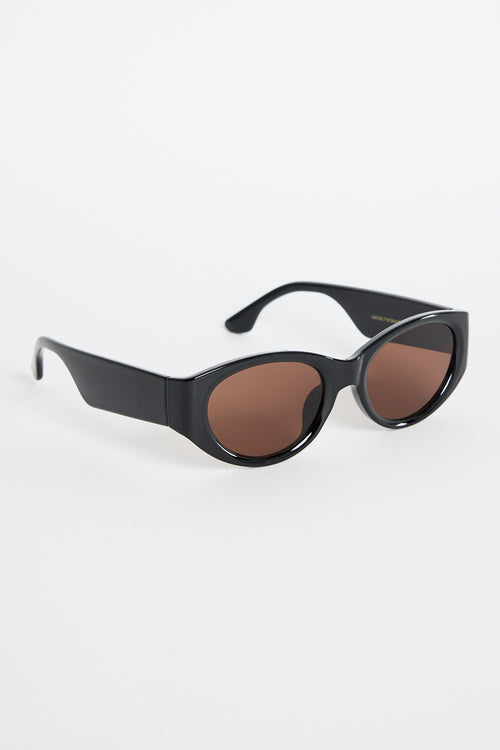 Glossy black cat-eye sunglasses with brown tinted lenses, photographed on a white background