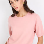 Woman wearing a pink sweater against a white background