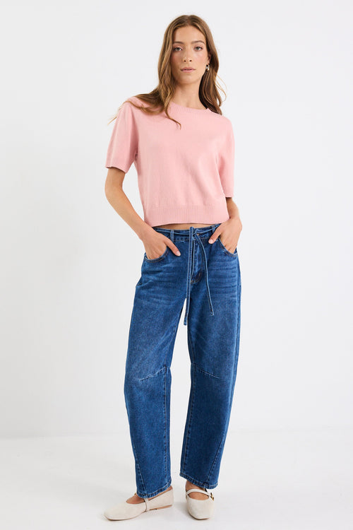 Woman wearing a pink top and blue jeans on a white background