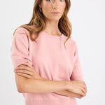 Woman wearing a pink sweater and blue jeans on a white background