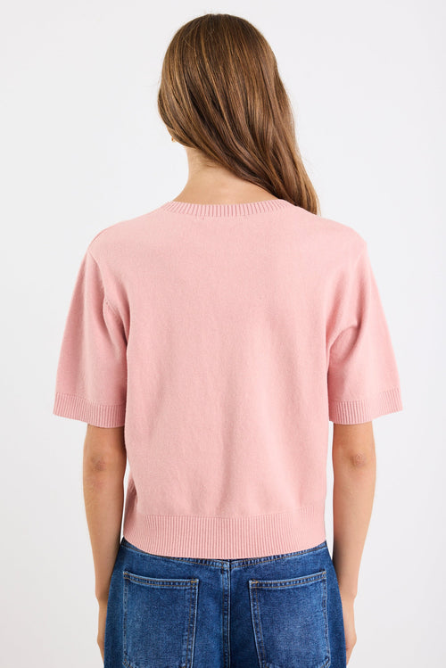 Person wearing a pink sweater and blue jeans on a white background