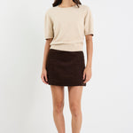 Woman wearing a beige sweater and brown skirt on a white background