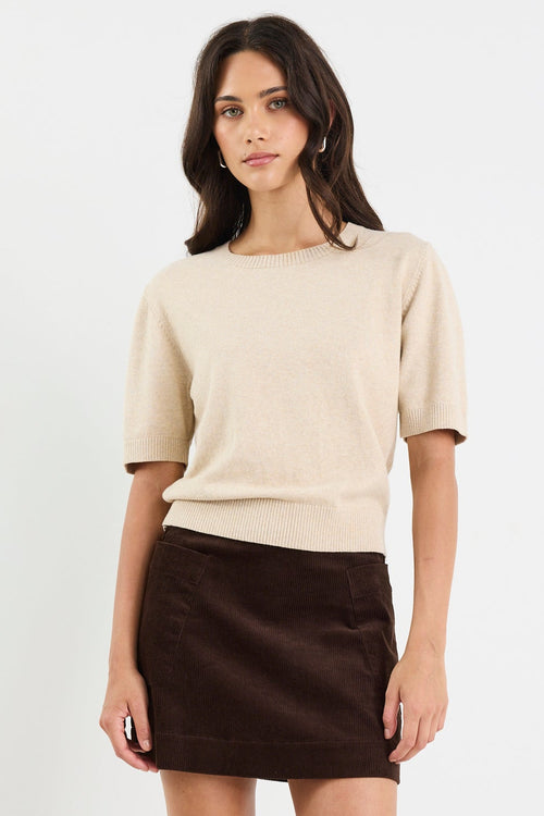 Woman wearing a beige top and brown skirt on a white background