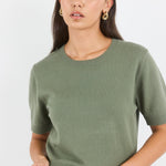 Woman wearing a green sweater against a white background