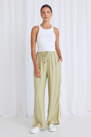 model wears green pants with a white tank