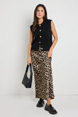 Woman wearing a leopard print satin maxi skirt, styled with a black knit top for a chic, bold look.