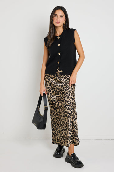 Woman wearing a leopard print satin maxi skirt, styled with a black knit top for a chic, bold look.