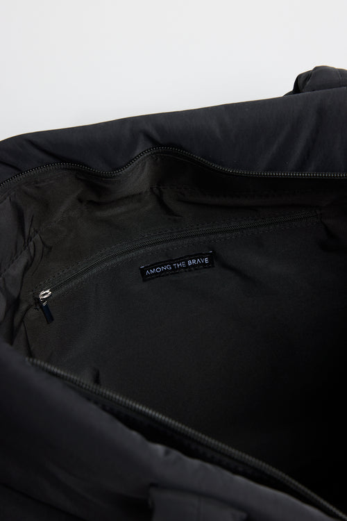 Black quilted tote bag with padded handles, photographed standing upright against a light background.