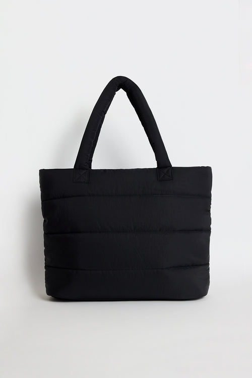 Black quilted tote bag with padded handles, photographed standing upright against a light background.