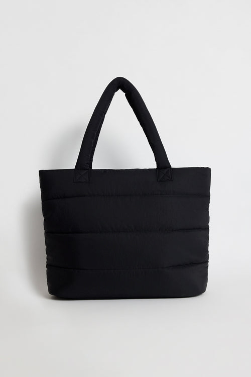 Black quilted tote bag with padded handles, photographed standing upright against a light background.