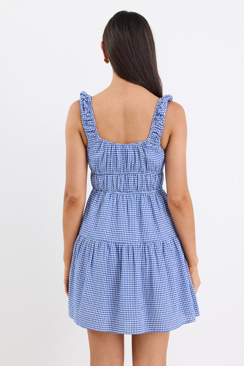 A sleeveless electric blue and white gingham mini dress with tiered detailing, tie-front feature, and a flattering fit. Fully lined for comfort, made from a 50% Cotton and 50% Viscose blend.