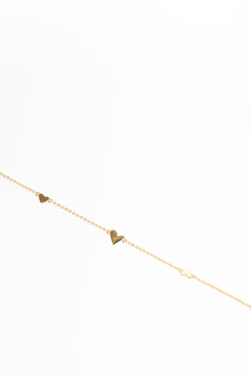 Gold anklet with heart-shaped charms on a white background