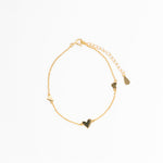 Gold bracelet with heart-shaped charms on a white background