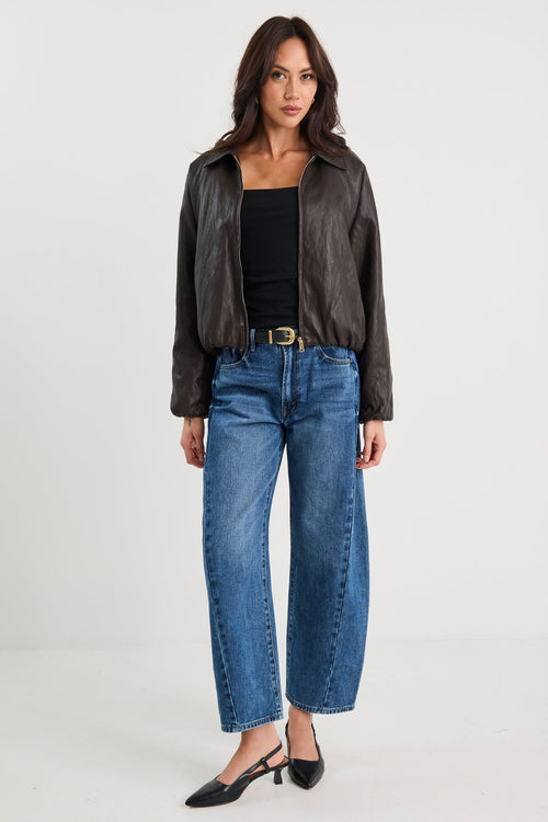 Woman wearing a black leather jacket and blue jeans on a white background