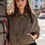 Woman in a brown jacket standing on a city street